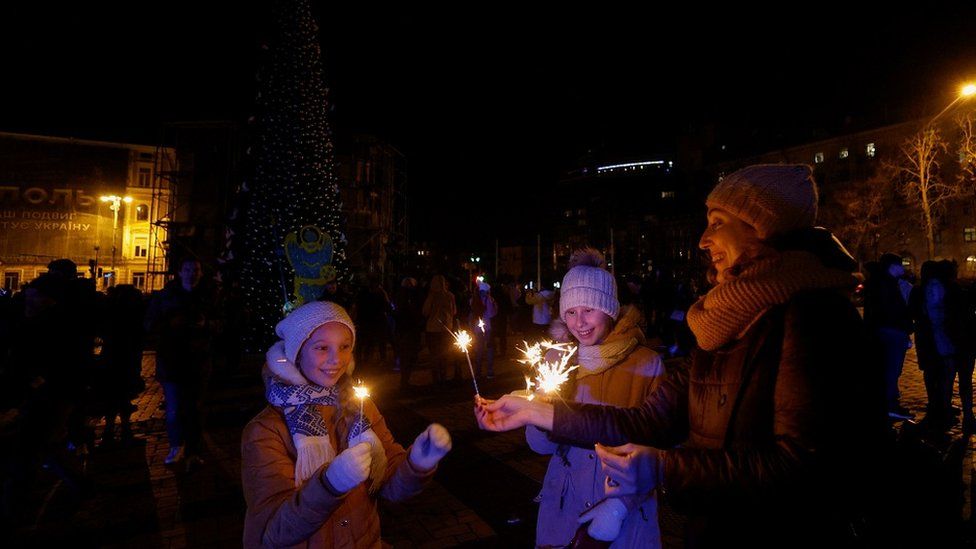 People gathered next to a Christmas tree to celebrate the New Year eve before a curfew, amid Russia's attack on Ukraine, in front of the St. Sophia Cathedral in Kyiv, Ukraine