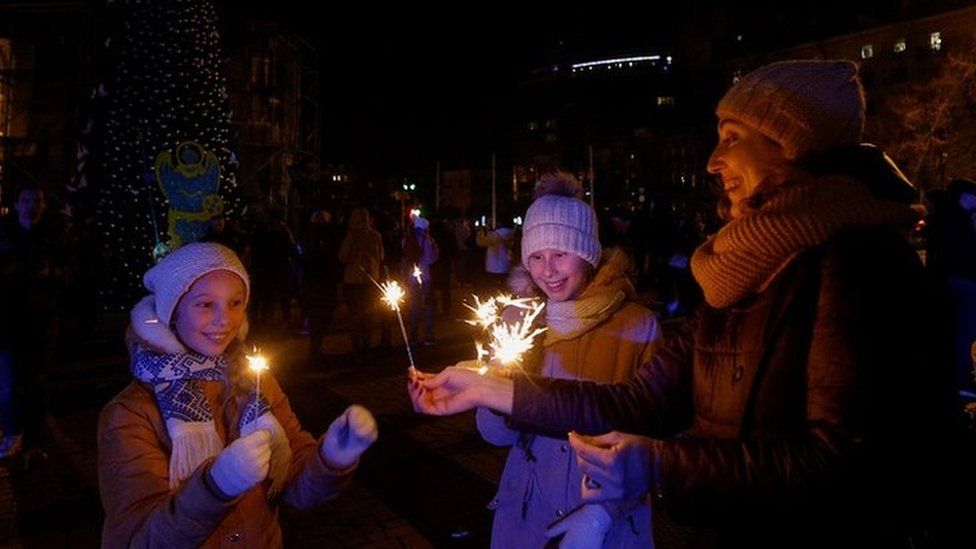 People gathered next to a Christmas tree to celebrate the New Year eve before a curfew, amid Russia's attack on Ukraine, in front of the St. Sophia Cathedral in Kyiv, Ukraine