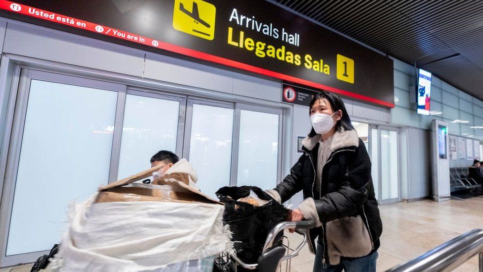 A woman pushes a luggage trolley in a Spanish airport terminal