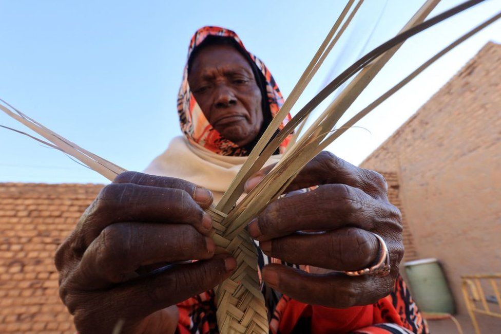 A Sudanese woman weaves palm leaves (al-Zaaf), a traditional skill of making baskets, food trays and other household items, in the village of Al-Saqqai, some 57km north of the capital Khartoum, on January 4, 2023