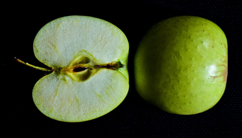 face up and face down halves of green apple on black