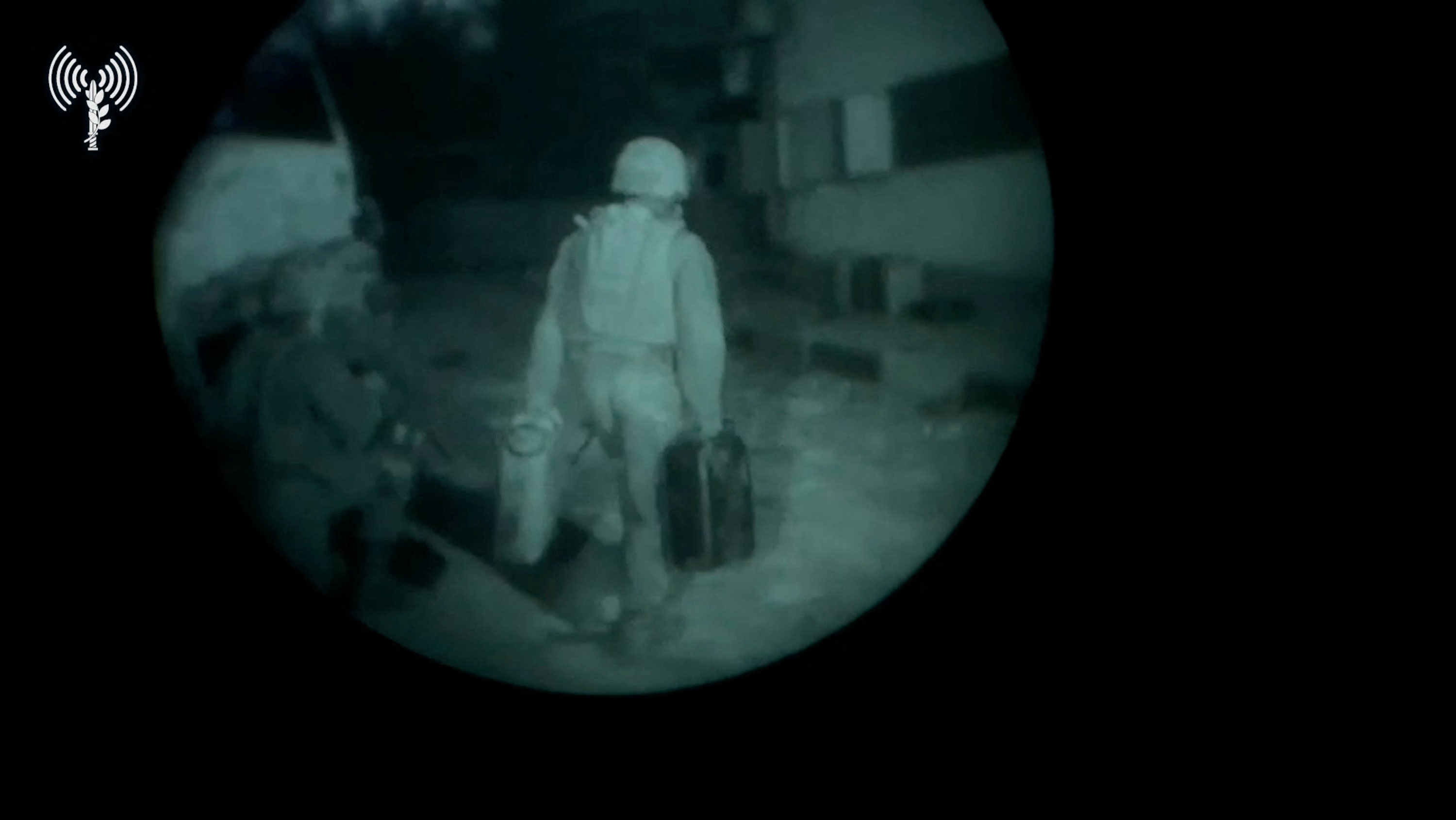 An Israeli army soldier walks towards a building structure carrying gallon containers, as they say, while delivering fuel to Al Shifa hospital, in a location given as Gaza, in this screengrab taken from a handout video released on November 12.